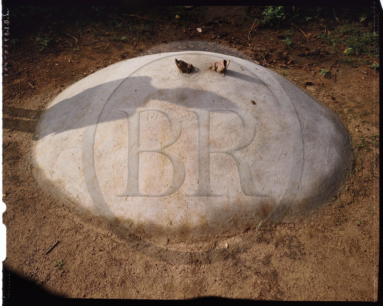 Burkina Faso, province de Poni, pays des Lobi, région de Loropéni, Lakar, tombe d'un enfant par l'ombre de son père, la plupart des tombes comportent un ou plusieurs éléments ayant appartenus au défunt, ici il s'agit des sandales de l'enfant mais le plus souvent on trouve, scellés dans la tombe, la vaisselle du disparu (bol, assiette et même fourchette)