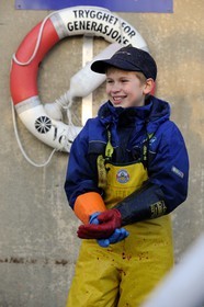 Norway, Nordland County, Vesteralen Islands, Myre harbour, young boy working in cod factory to have pocket money