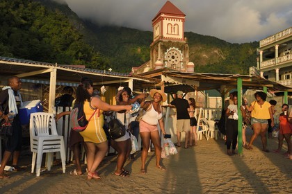 Caribbean, Dominica Island, Soufriere Bay, the village of Soufriere, rum bar on the beach and catholic Church of Saint Mark in the background