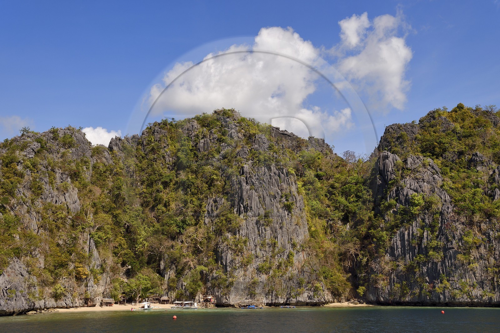 Philippines, Calamian Islands dans le nord de Palawan, Coron Island Natural Biotic Area, pirogue à balancier au pied des murs géants des falaises de calcaire