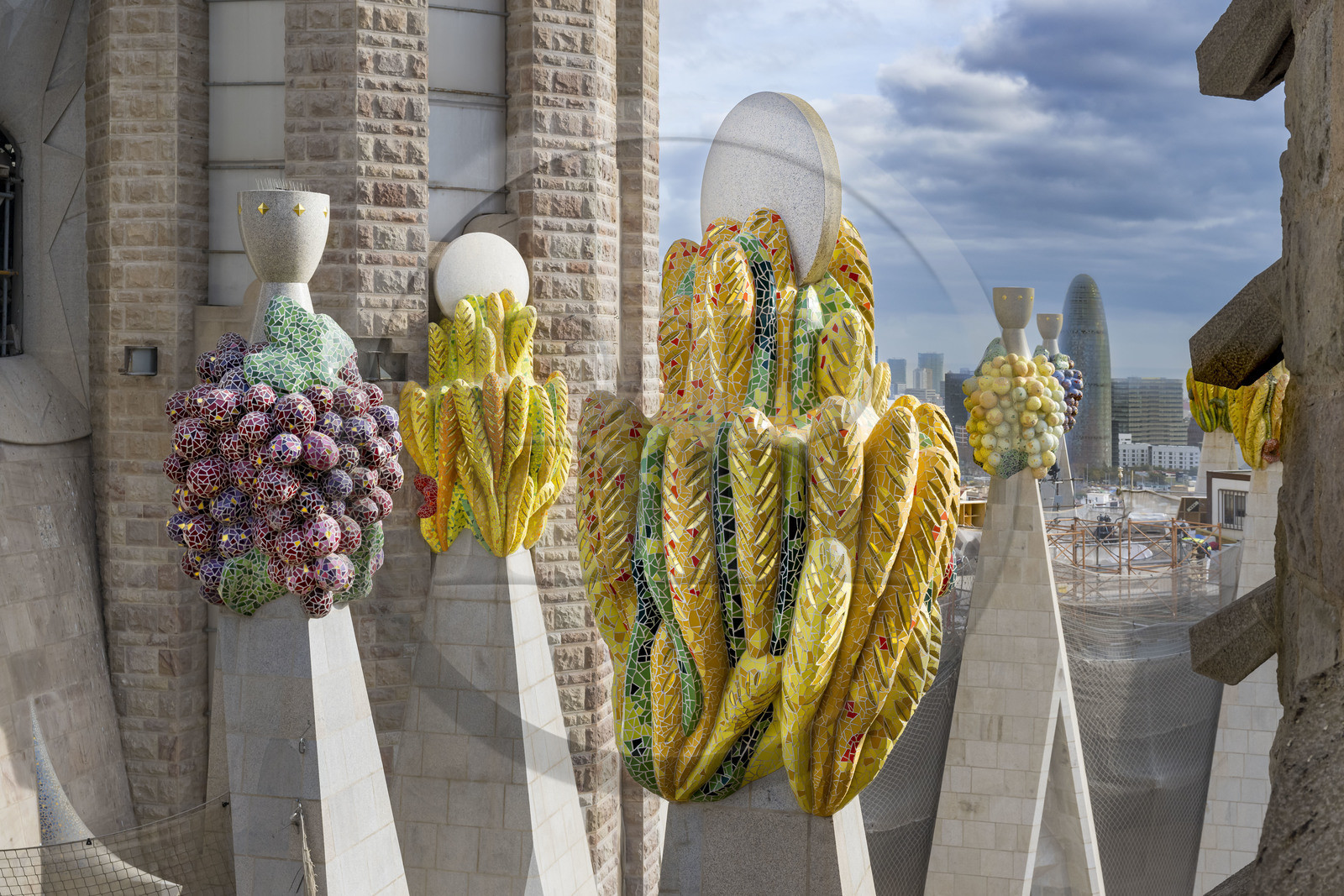 Espagne, Catalogne, Barcelone, quartier de l'Eixample, basilique de la Sagrada Familia de l'architecte du modernisme catalan Antoni Gaudi classée Patrimoine Mondial de l'UNESCO, sommets surmontés de mosaïques en forme de fruits, la Torre Agbar de l'architecte Jean Nouvel en arrière plan