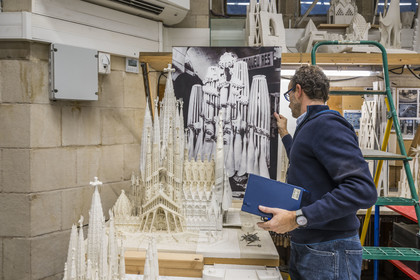 Espagne, Catalogne, Barcelone, quartier de l'Eixample, basilique de la Sagrada Familia de l'architecte du modernisme catalan Antoni Gaudi classée Patrimoine Mondial de l'UNESCO, l'atelier maquettes, l'architecte et coordinateur de l'équipe des artistes et des maquettistes Jeronimo Buxareu Padros présente les prochains travaux à entreprendre, la future facade de la Gloire face à lui et la photo de la maquette originale de Gaudi en arrière plan