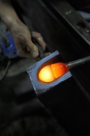 France, Moselle (57), Meisenthal, Thibaut souffleur au Centre international d’Art verrier (CIAV) s’aide d’une mailloche en bois pour arrondir le verre et faire une boule de Noël en verre régulière
