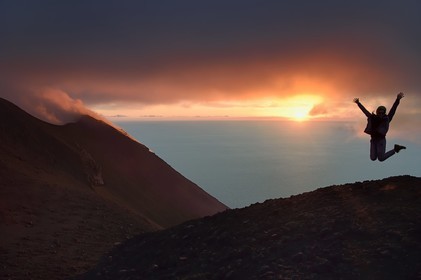 Italie, Sicile, iles Eoliennes, classées Patrimoine Mondial de l'UNESCO, ile de Stromboli, randonneur et fumerolles d'une éruption sur les pentes du volcan actif au coucher de soleil