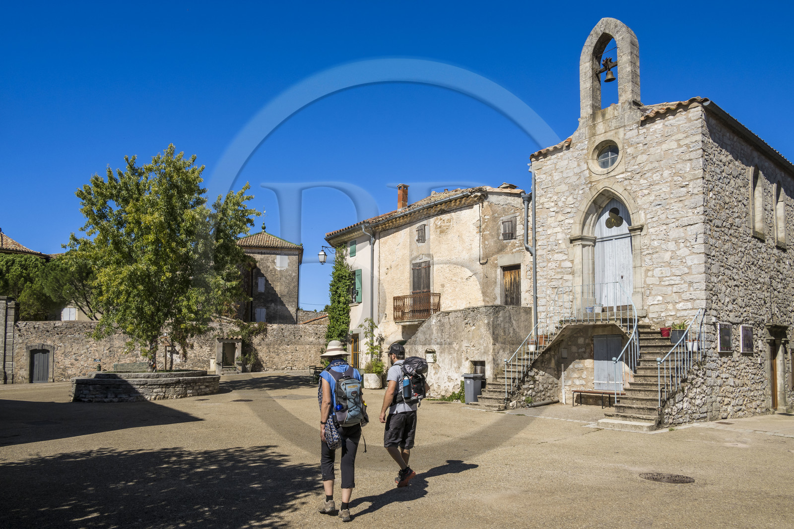France, Hérault (34), les Causses et les Cévennes, paysage culturel de l'agro-pastoralisme méditerranéen inscrit au Patrimoine Mondial de l'UNESCO, Saint-Maurice-Navacelles, randonneurs traversant la place de l'église