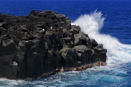 France, Ile de la Reunion, côte sud, Saint-Philippe, le Cap Méchant est situé le long d'une côte déchiquetée de roche volcanique frappée par la houle et typique de la région appelée Sud sauvage, pêcheur sur un rocher
