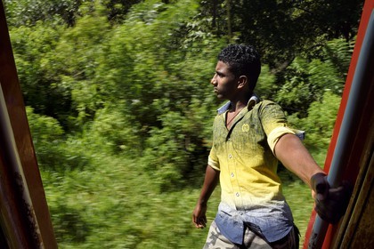Sri Lanka, Uva Province, the popular scenic train ride through the tea growing hill country between Badulla and Ella, passenger hanging on the door