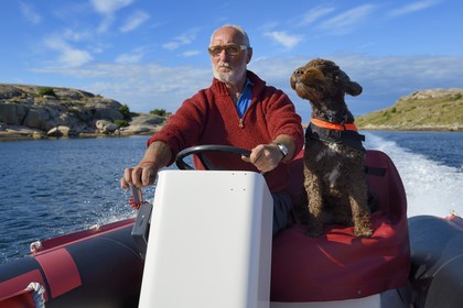 Suède, Västra Götaland, Smögen, Cyril et son chien Simpson à bord de son zodiac