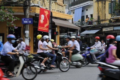 Vietnam, Hanoï, circulation en moto dans la vieille ville sous le regard d' Ho Chi Minh
