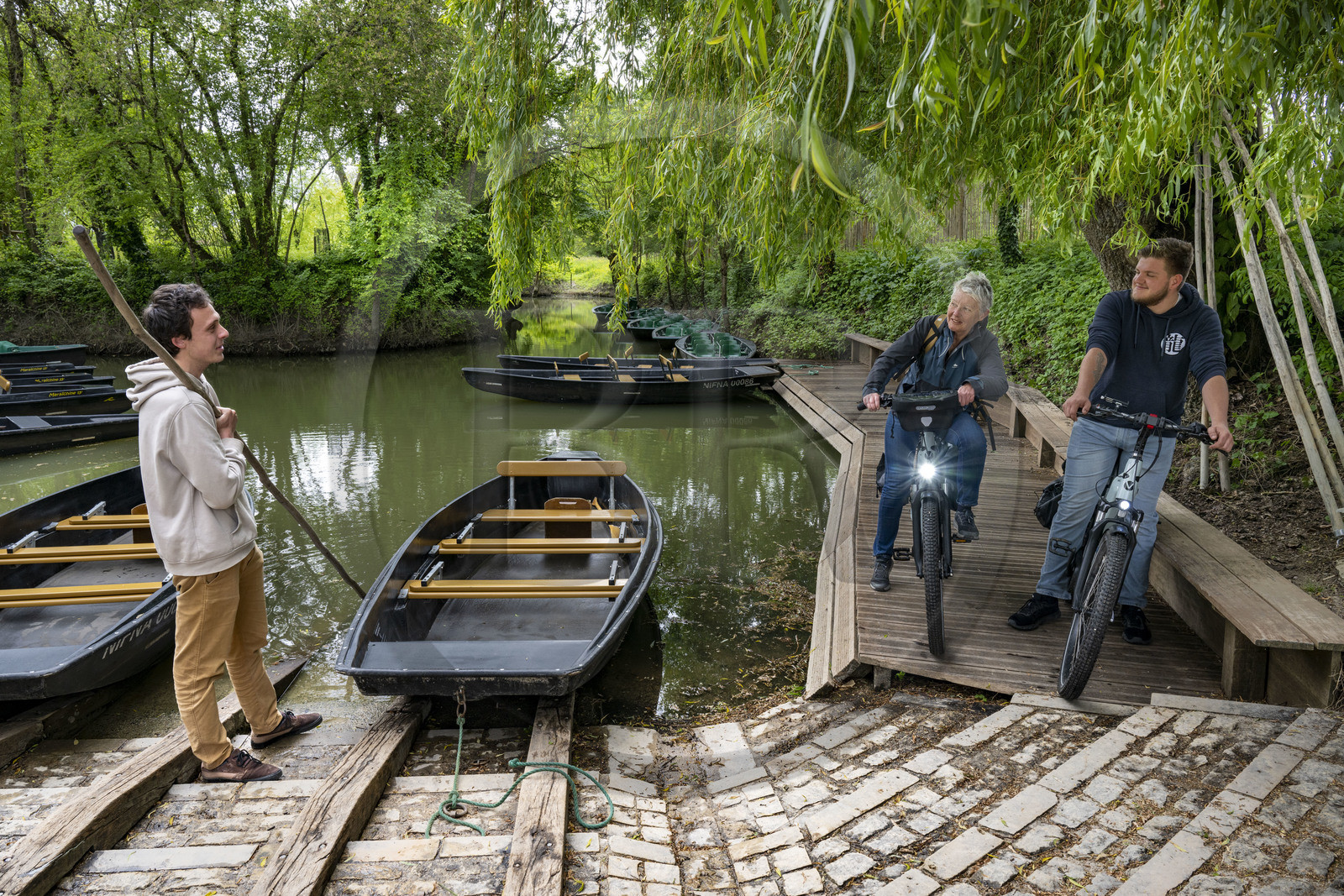 France, Vendée (85), Maillezais, cycliste en discussion avec un batelier tenant sa pigouille (perche en bois) au Grand Port, embarcadère de l'Abbaye