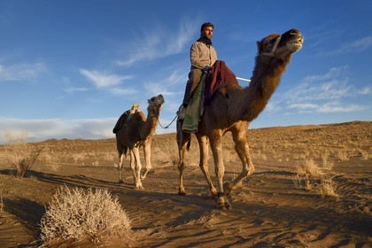 Iran, Isfahan province, Dasht-e Kavir desert, Mesr in Khur and Biabanak County, man riding his camel in the desert at sunset