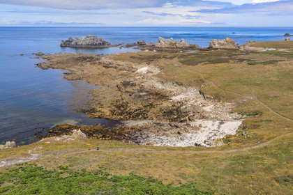 France, Finistère, Iroise Sea, Ouessant Island, hiker on the coastal path, the beach and Yuzin anchorage in the background (aerial view)