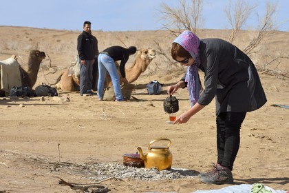Iran, Isfahan province, Dasht-e Kavir desert, Mesr in Khur and Biabanak County, camel trek, woman serving tea at lunchtime