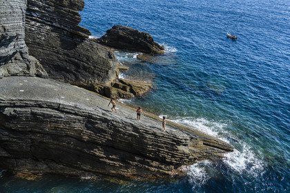Italie, Ligurie, Cinque Terre, parc national des Cinque Terre classé Patrimoine Mondial de l'UNESCO, village de Vernazza, jeunes gens plongeant d'un rocher au pied du village