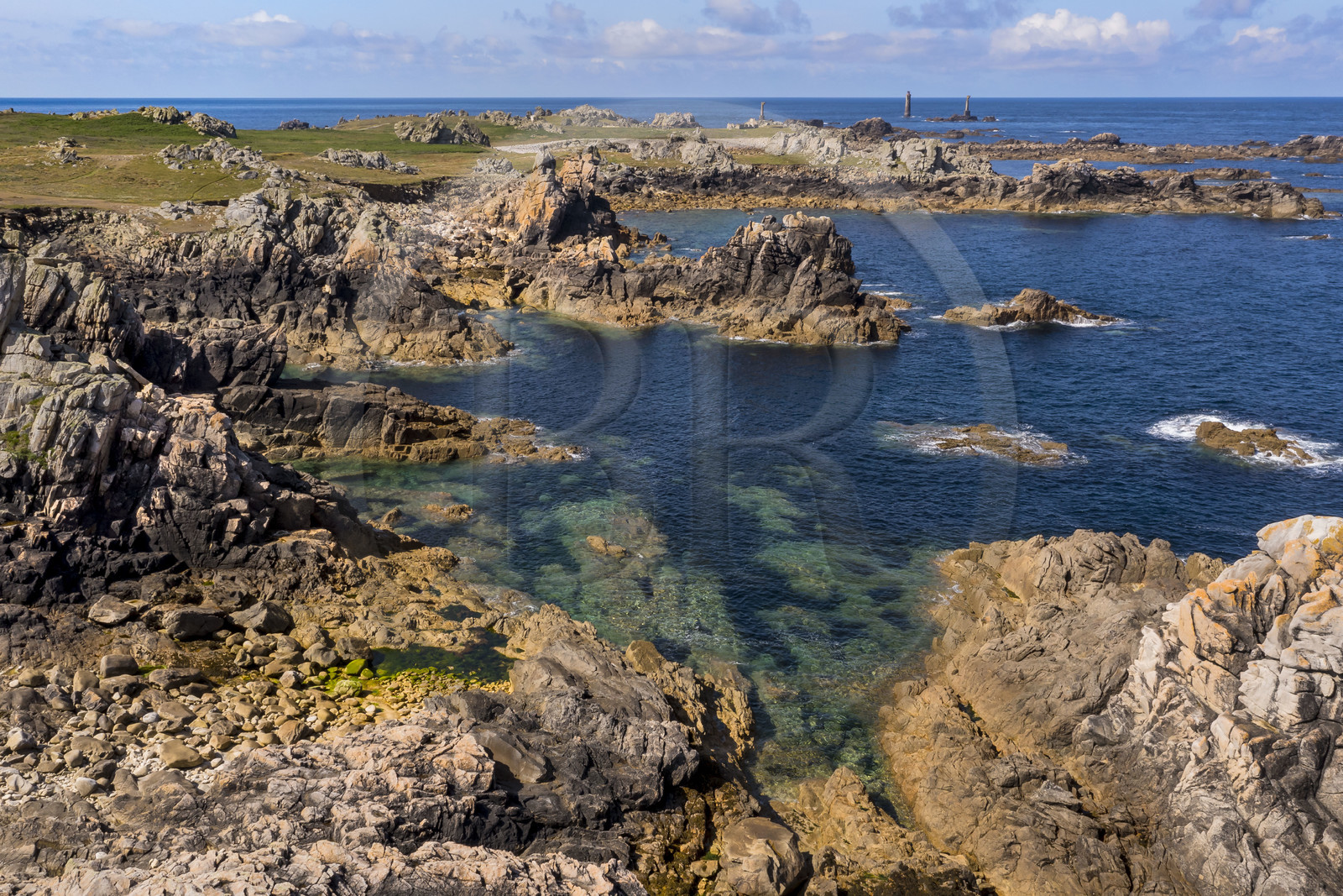 France, Finistère (29), Mer d'Iroise, Ile d'Ouessant, rochers façonnés par les tempêtes au pied du phare du Créac’h, le phare de Nividic sur la Pointe de Pern en arrière plan (vue aérienne)