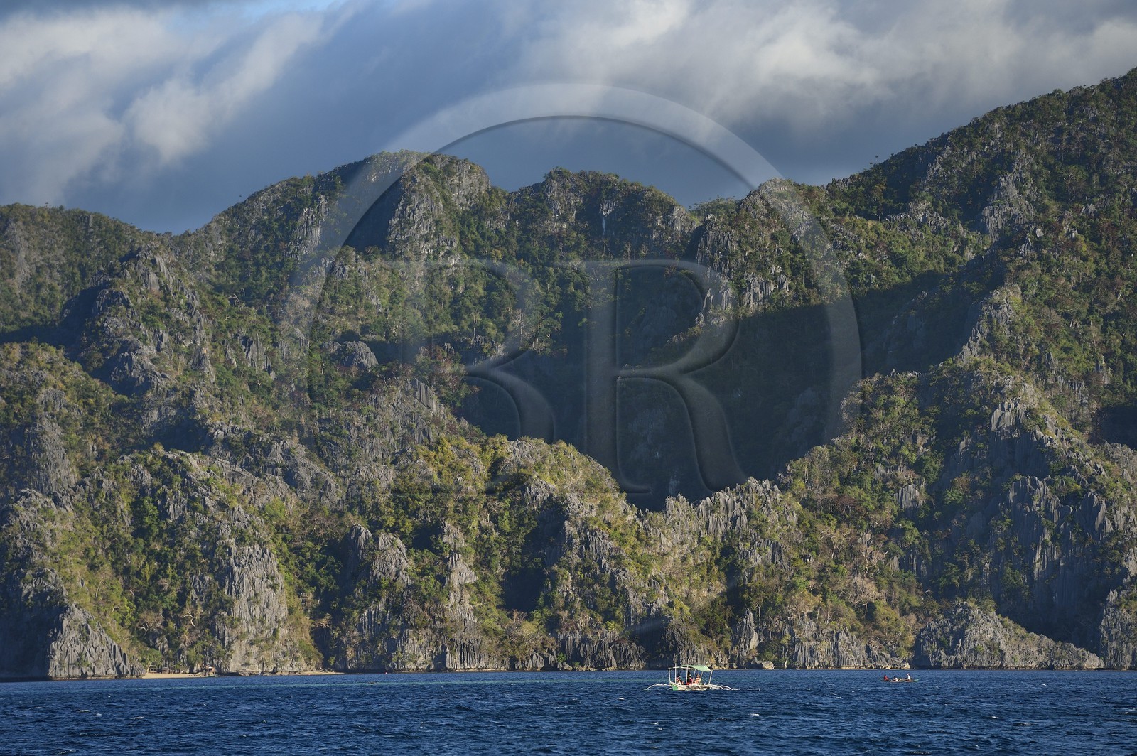 Philippines, Calamian Islands dans le nord de Palawan, Coron Island Natural Biotic Area, pirogue à balancier au pied des murs géants des falaises de calcaire du Permien d'origine jurassique Philippines, Calamian Islands dans le nord de Palawan, Coron Island Natural Biotic Area, pirogue à balancier au pied des murs géants des falaises de calcaire du Permien d'origine jurassique