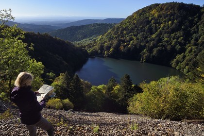 France, Haut Rhin, Ballons des Vosges Regional Natural Park, Rimbach pres Masevaux, hiker walking on the GR5 hiking trail over the Lac des Perches, the plain of Alsace and the Alps in the background