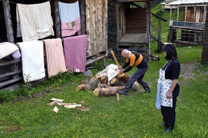 Georgia, Kakheti, Tusheti National Park, village of Shenako, Soso Pirashvili who splits the wood and Lia Otarashvili in front of their summer house