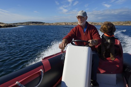 Sweden, Västra Götaland, Smögen, Cyril and his dog Simpson aboard his zodiac