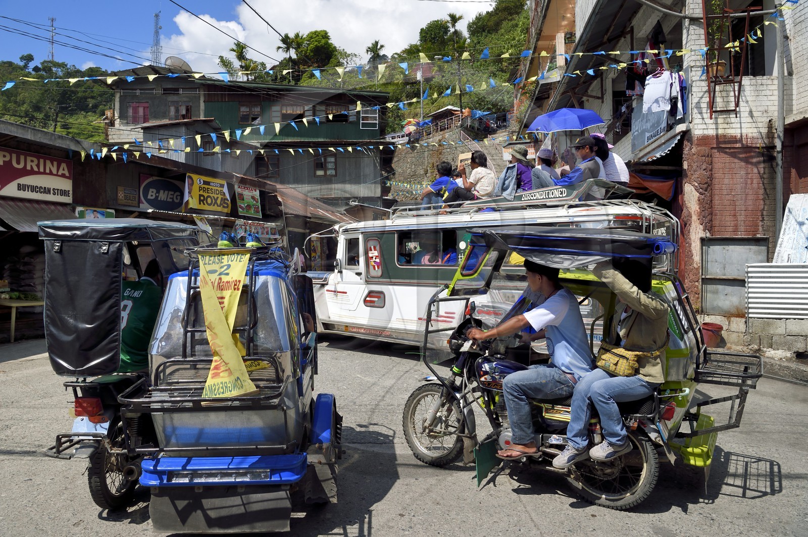 Philippines, province d'Ifugao, ville de Banaue, jeepney (jeep allongée pour le transport de passagers) et tricycle moto-taxi sur la place principale, passagers sur le toit