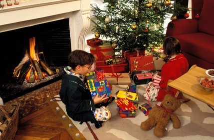 France, Noël, enfants assis devant la cheminée avec leurs cadeaux