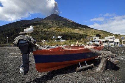 Italy, Sicily, Aeolian Islands, listed as World Heritage by UNESCO, Stromboli island, one of the multiple and regular eruptions of the Stromboli volcano which rises to 924m, fishing boat on the beach of Scari in the foreground
