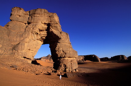 Libye, région du désert, Le Fezzan (Sahara), Touareg sous l'arche (en grès) de Afazedjar dans la Tadrart-Akakus