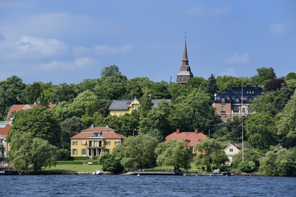 Sweden, Stockholm, Djurgarden, seaside villas and the Hallestad belfry in the open air museum Skansen in the background