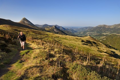 France, Cantal, Parc Naturel Régional des Volcans d'Auvergne (regional nature park of Auvergne volcanoes), Le Lioran, col de Rombiere (mountain pass) overlooking the Jordanne valley, hiker on the Way of St. James to Santiago de Compostela by Via Arverna, in the background the Puy Griou emerging on the left and the Griounou on its right