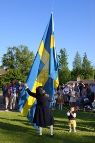 Sweden, Dalarna County, Leksand area, Midsummer celebrations in the tiny hamlet of Hjulbäck, raising the Swedish flag