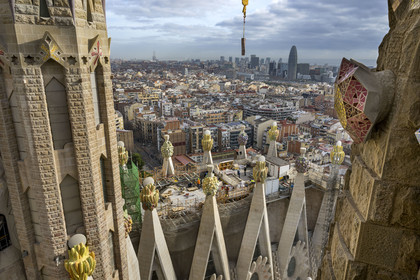 Espagne, Catalogne, Barcelone, quartier de l'Eixample, basilique de la Sagrada Familia de l'architecte du modernisme catalan Antoni Gaudi classée Patrimoine Mondial de l'UNESCO, sommets surmontés de mosaïques en forme de fruits entourant le chantier sur le toit de la nef à l'arrière de la future facade de la Gloire, la Torre Agbar de l'architecte Jean Nouvel en arrière plan