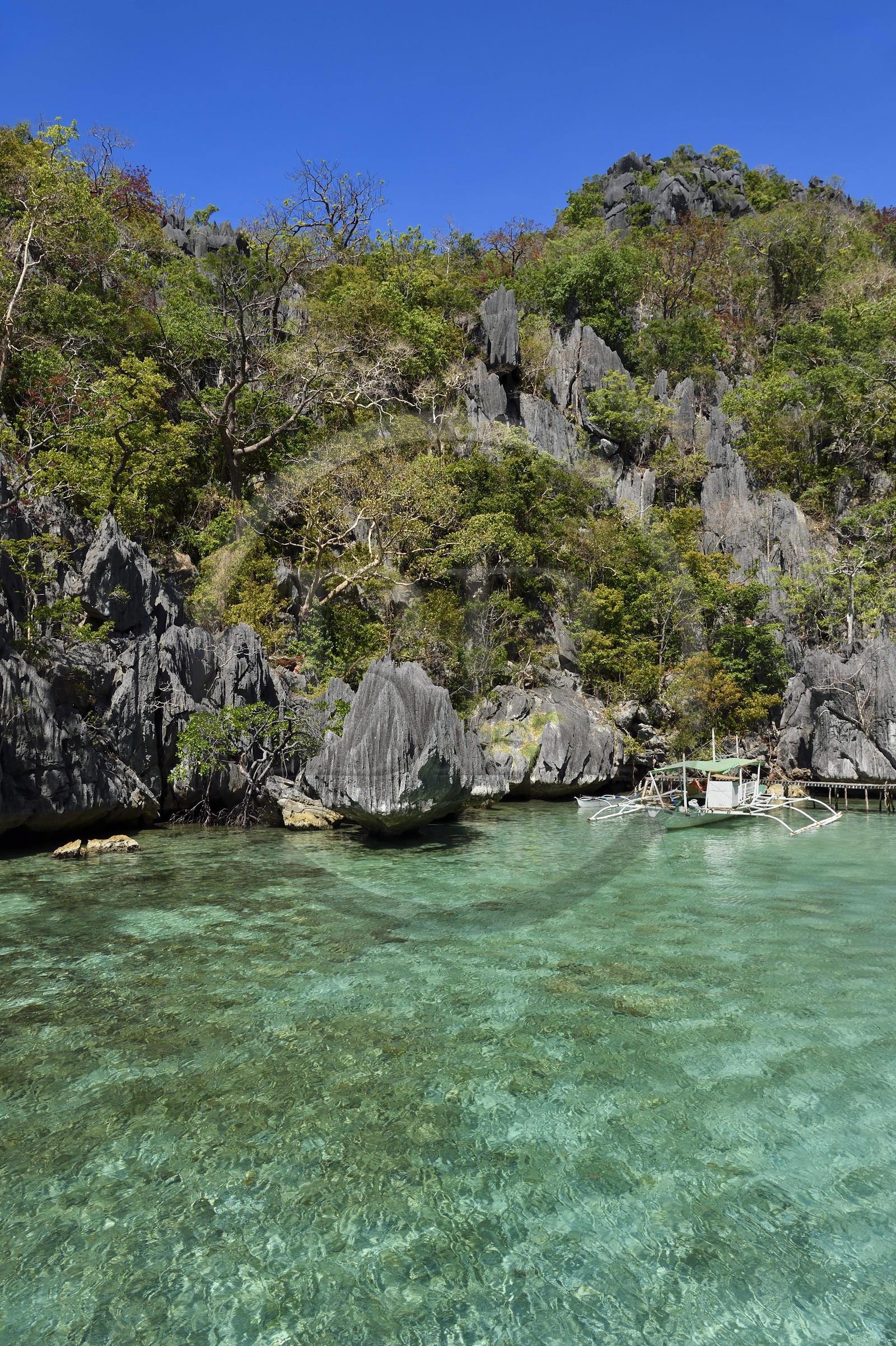 Philippines, Calamian Islands dans le nord de Palawan, Coron Island Natural Biotic Area, pirogue à balancier au pied des rochers de calcaire