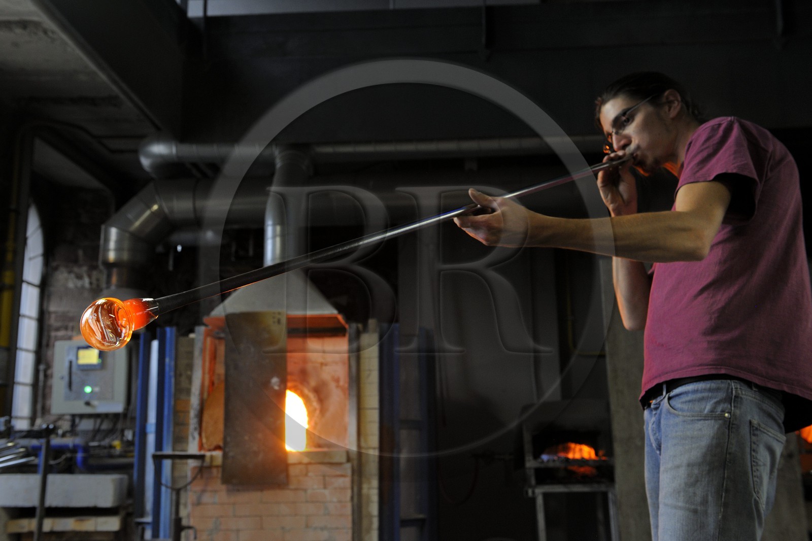 France, Moselle (57), Meisenthal, Thibaut souffleur au Centre international d’Art verrier (CIAV), fabrication d'une boule de Noël en verre. Tout en tournant la canne, il souffle dans la canne