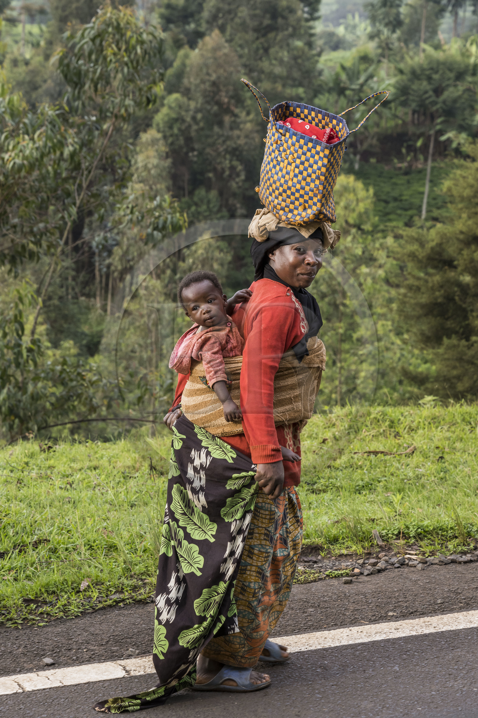 Rwanda, Province de l’Ouest, Mwaga, femme transportant son enfant dans le dos et portant son sac sur la tête