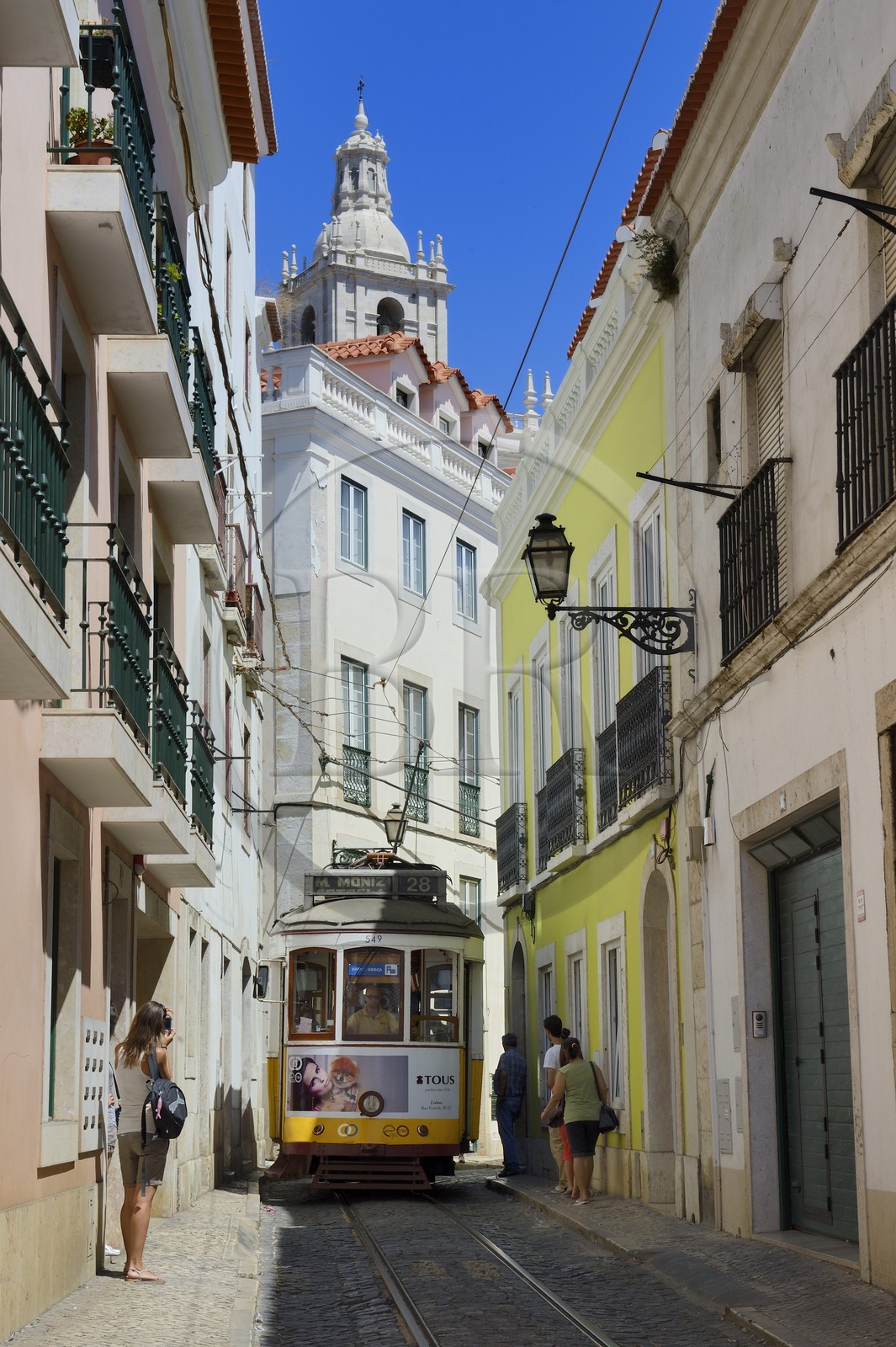 Portugal, Lisbon, Alfama district, tram (electricos) along Rua das Escolas Gerais with the tower of Sao Vicente de Fora church