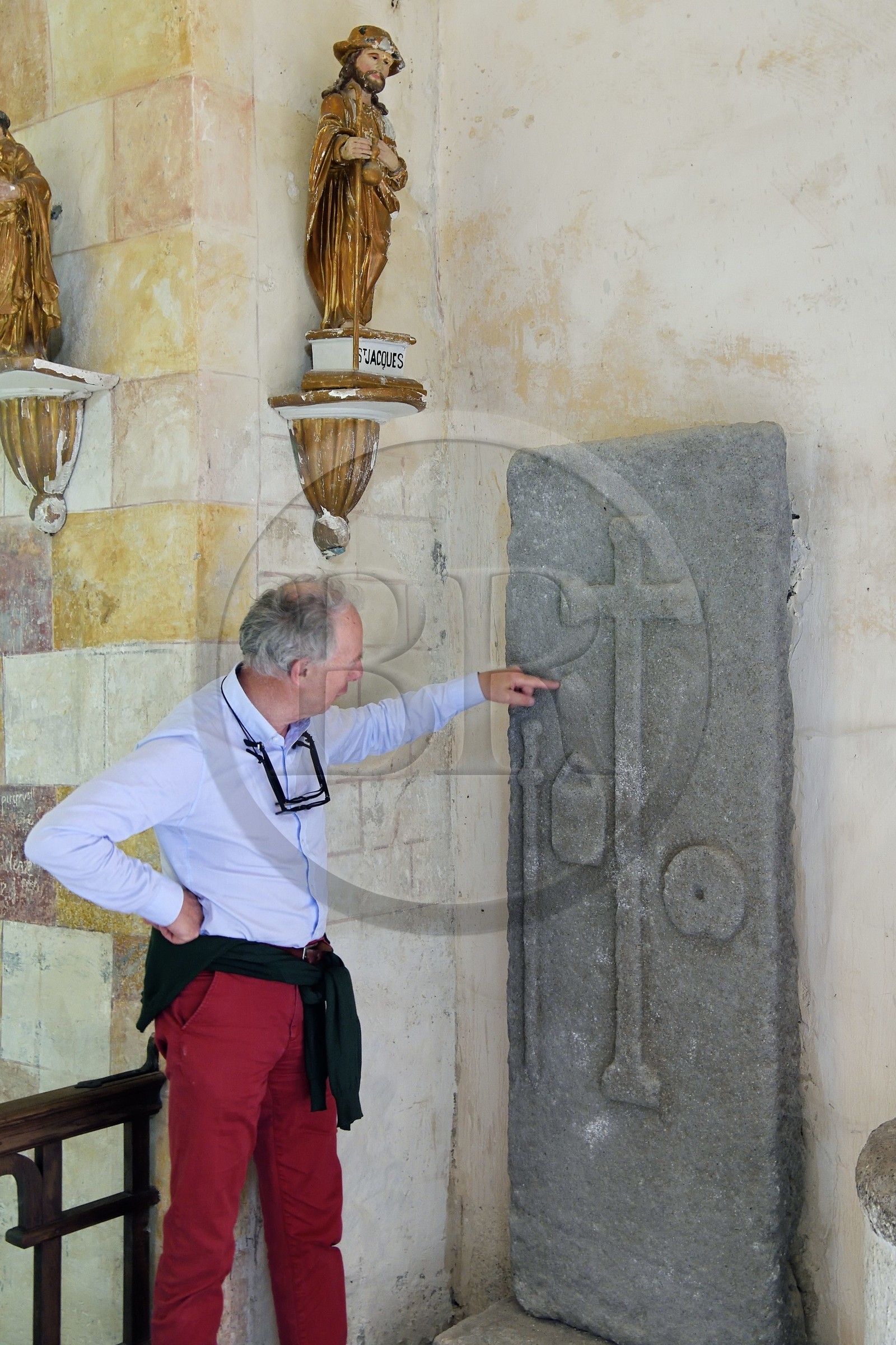 France, Cantal (15), étape sur le chemin de Saint-Jacques de Compostelle par la Via Arverna, Neussargues-Moissac, église Saint-Hilaire du XIIe siècle, tombe d'un pélerin du XVIIe siècle ayant effectué le chemin de St Jacques de Compostelle, dalle funéraire avec le bourdon, le sac et la coquille autour de la croix funéraire, le conservateur en chef du patrimoine Humbert Jacomet