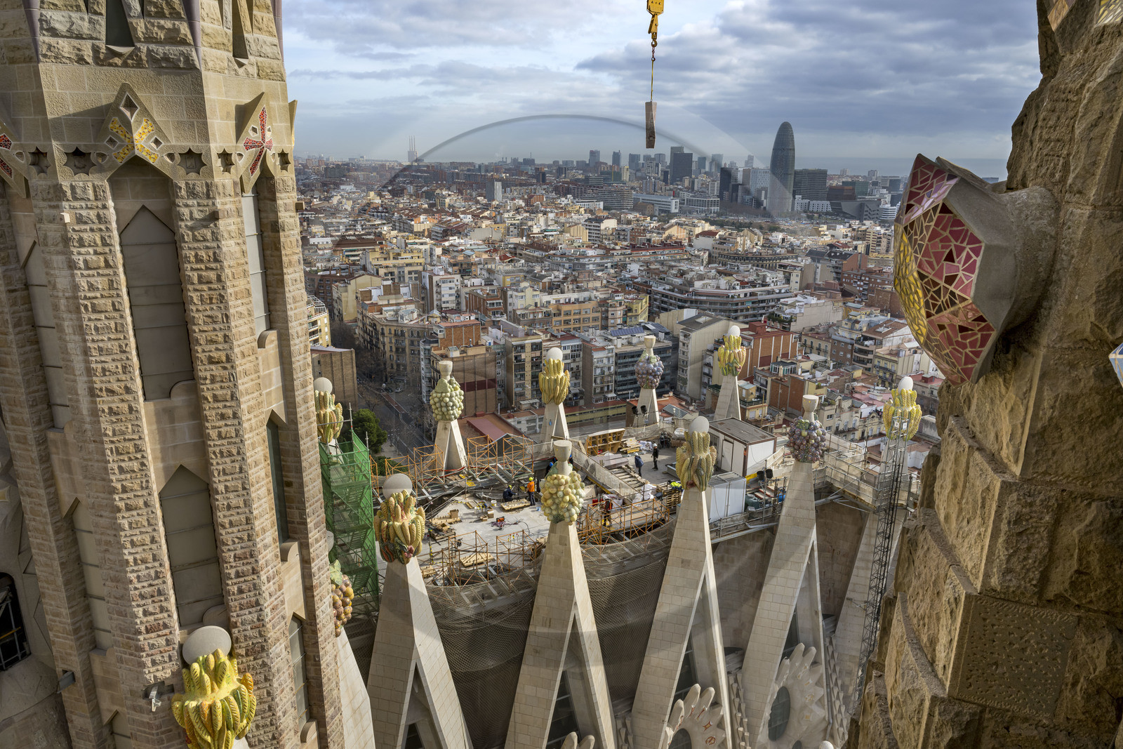 Espagne, Catalogne, Barcelone, quartier de l'Eixample, basilique de la Sagrada Familia de l'architecte du modernisme catalan Antoni Gaudi classée Patrimoine Mondial de l'UNESCO, sommets surmontés de mosaïques en forme de fruits entourant le chantier sur le toit de la nef à l'arrière de la future facade de la Gloire, la Torre Agbar de l'architecte Jean Nouvel en arrière plan