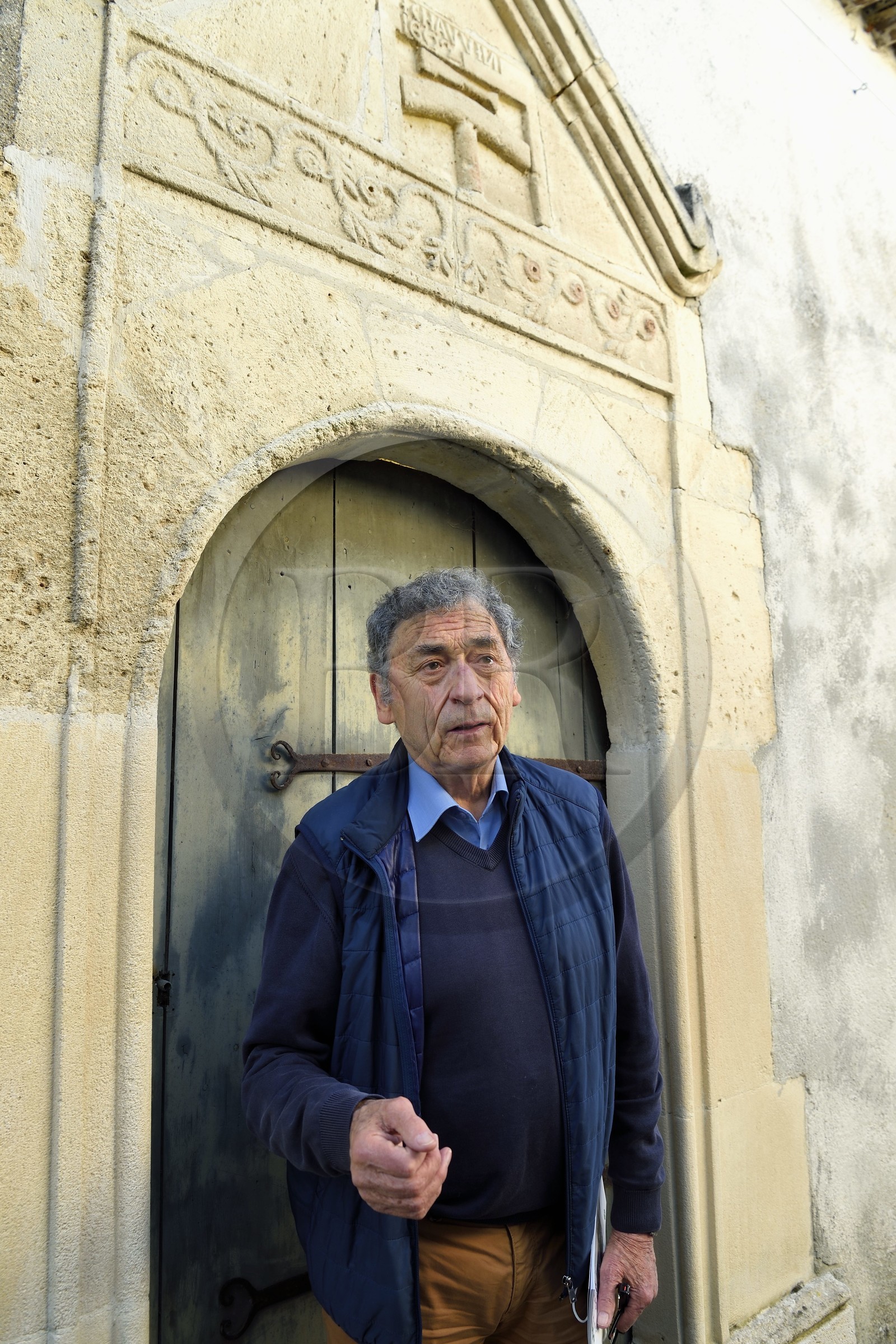 France, Charente (16), Saint-Simon,le maire du village gabarrier Jean Jacques Delage devant une porte et enseigne d'un artisan calfat qui participait à la construction des gabarres (datée de 1602), il remplissait d'étoupe les fentes des bateaux avant de les recouvrir de poix, résine et goudron
