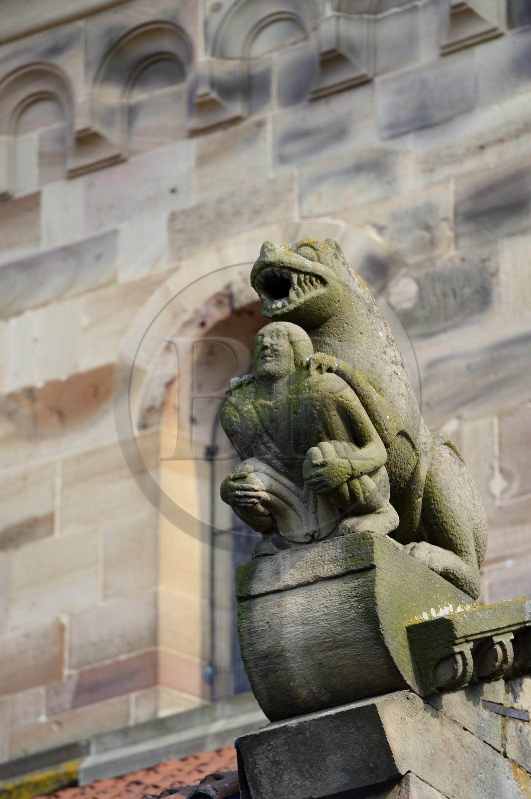 France, Bas-Rhin (67), Rosheim, église romane Saint-Pierre et St-Paul, sculpture en bosses rondes, l'acrotère luxurieux symbolise le péché, un homme richement vêtu apparait écrasée par un lion menacant