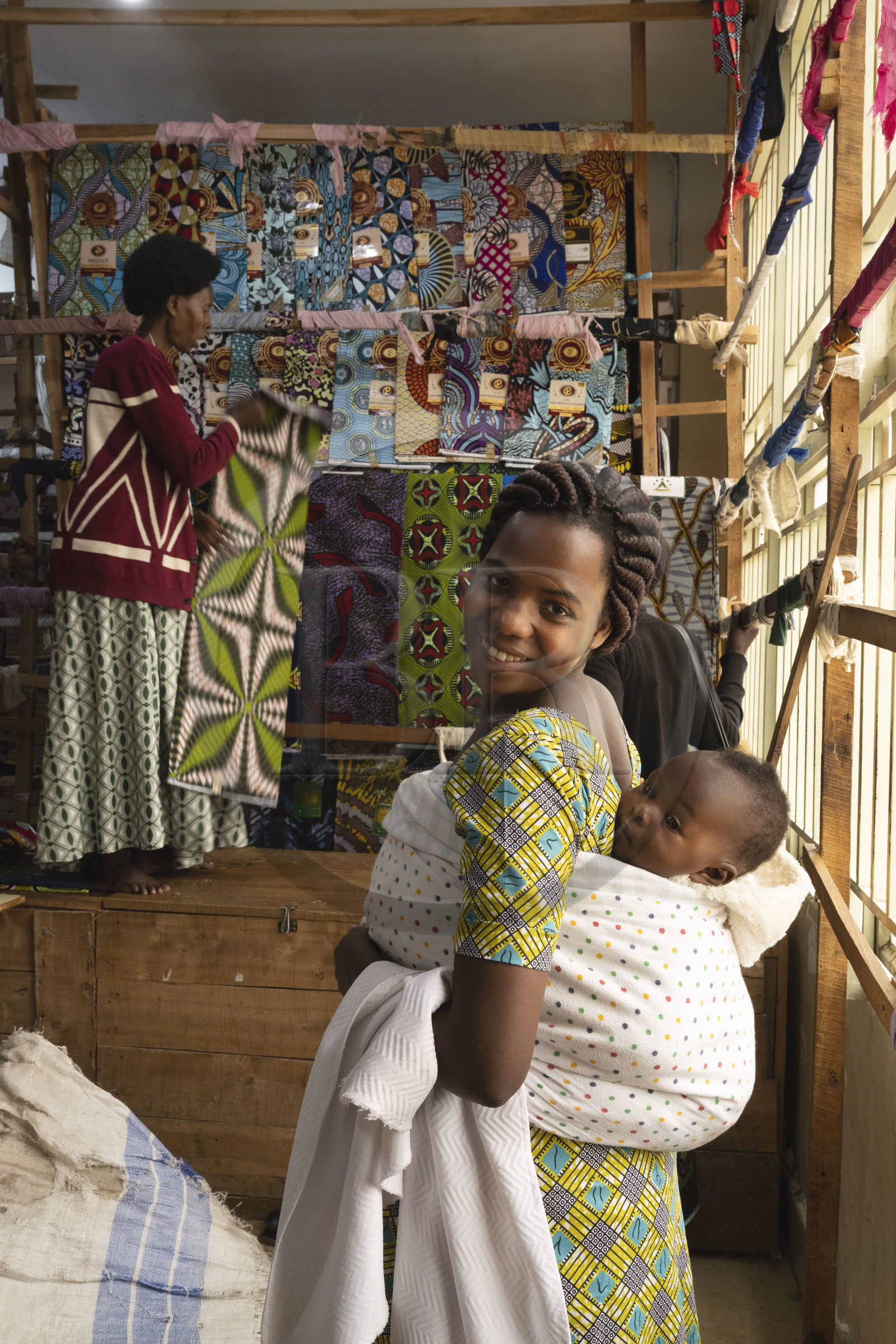 Rwanda, Province du Nord, Musanze (anciennement nommée Ruhengeri), centre commercial Goico plaza, le couturière Joseline avec son bébé Elouange de 7 mois et sa tante en arrière plan qui vend les tissus