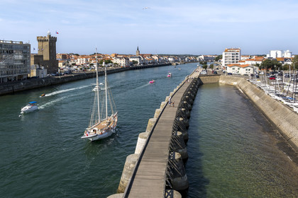 France, Vendee, Les Sables d'Olonne, boat in the access channel to the ports, the La Chaume district on the left with the 14th century Arundel Tower, a former keep converted into a lighthouse and maritime museum (aerial view)