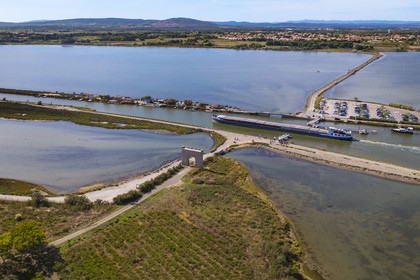France, Hérault (34), Villeneuve-lès-Maguelone (Palavas-Les-Flots), péniche sur le canal du Rhône à Sète passant la Passerelle du Pilou devant la Porte de Maguelone sur l'Ile de Maguelone, Villeneuve-lès-Maguelone en arrière plan (vue aérienne) France, Herault, Villeneuve les Maguelone (Palavas Les Flots), barge on the Rhone to Sète Canal passing the Passerelle du Pilou in front of the Porte de Maguelone on the Ile de Maguelone, Villeneuve les Maguelone in the background (aerial view)