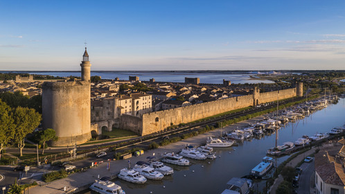 France, Gard (30), Aigues-Mortes, la ville médiévale entourée par ses remparts, la Tour de Constance et le port du canal du Rhône à Sète au premier plan, les marais salants (Salins du Midi) en arrière plan (vue aérienne)