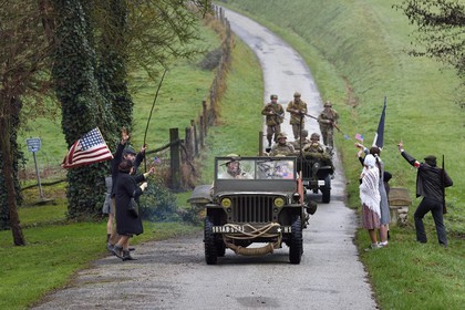 France, Eure, Sainte Colombe prés Vernon, Allied Reconstitution Group (US World War 2 and french Maquis historical reconstruction Association), reenactors in uniform of the 101st US Airborne Division progressing in a jeep Willys welcomed as liberators by villagers and FFI