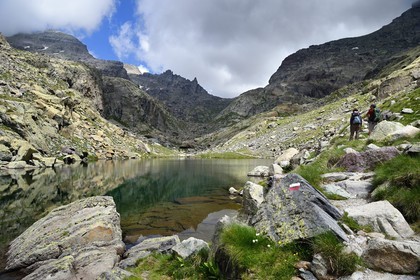 France, Alpes-Maritimes, parc national du Mercantour (Mercantour National Park), the Vallee des Merveilles (Valley of Wonders) scattered with thousands of rupestral engravings of the Bronze Age, hikers on the trail GR 52 at the Merveilles Lake below the Baisse (pass) de Valmasque and the Mont Grand Capelet (2915 m) in the background left