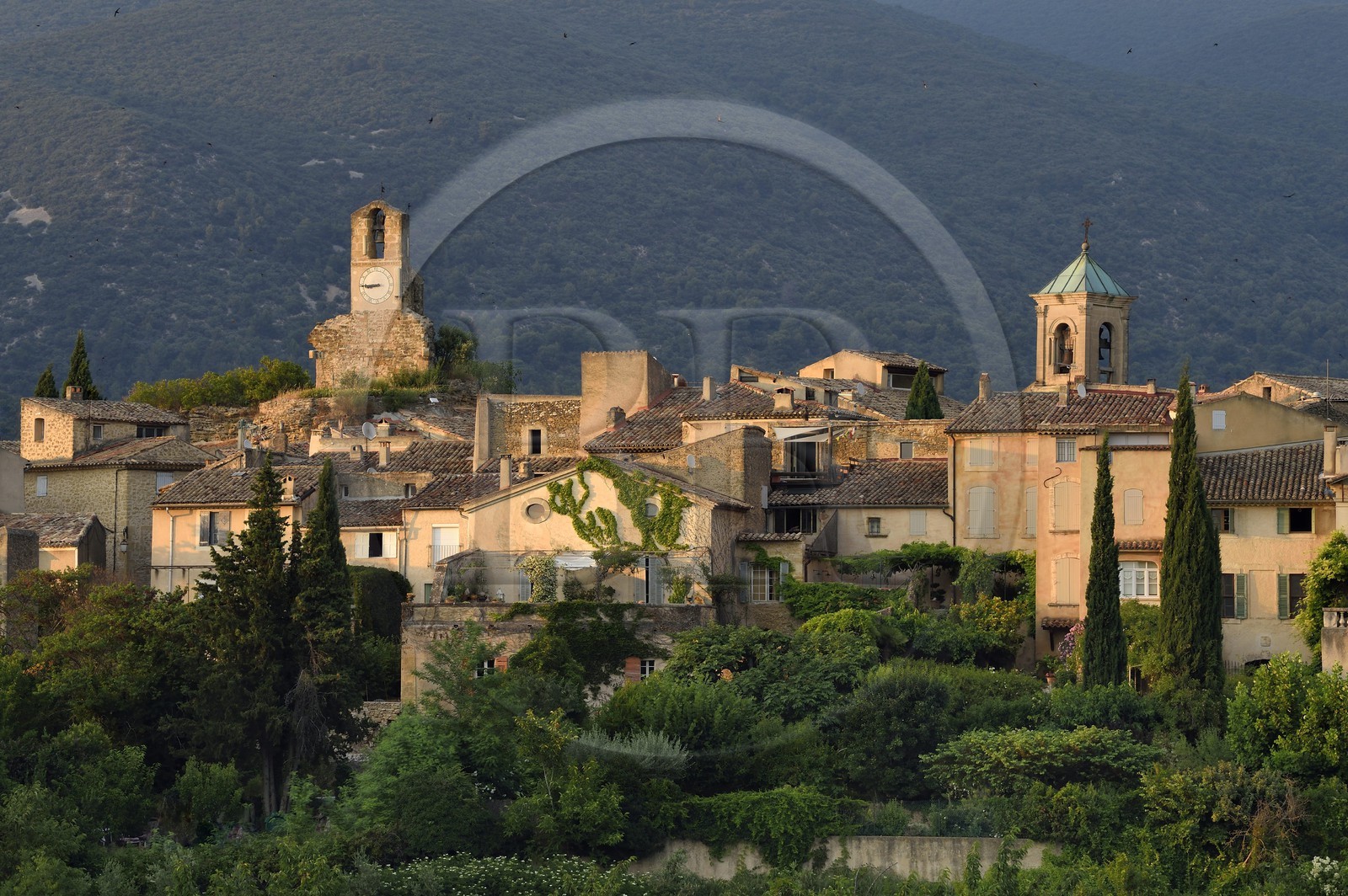 France, Vaucluse (84), Parc Naturel Regional du Luberon, Lourmarin, labellisé Les Plus Beaux Villages de France, la Tour de l'horloge et le chocher de l'église, le massif du Lubéron en arrière-plan