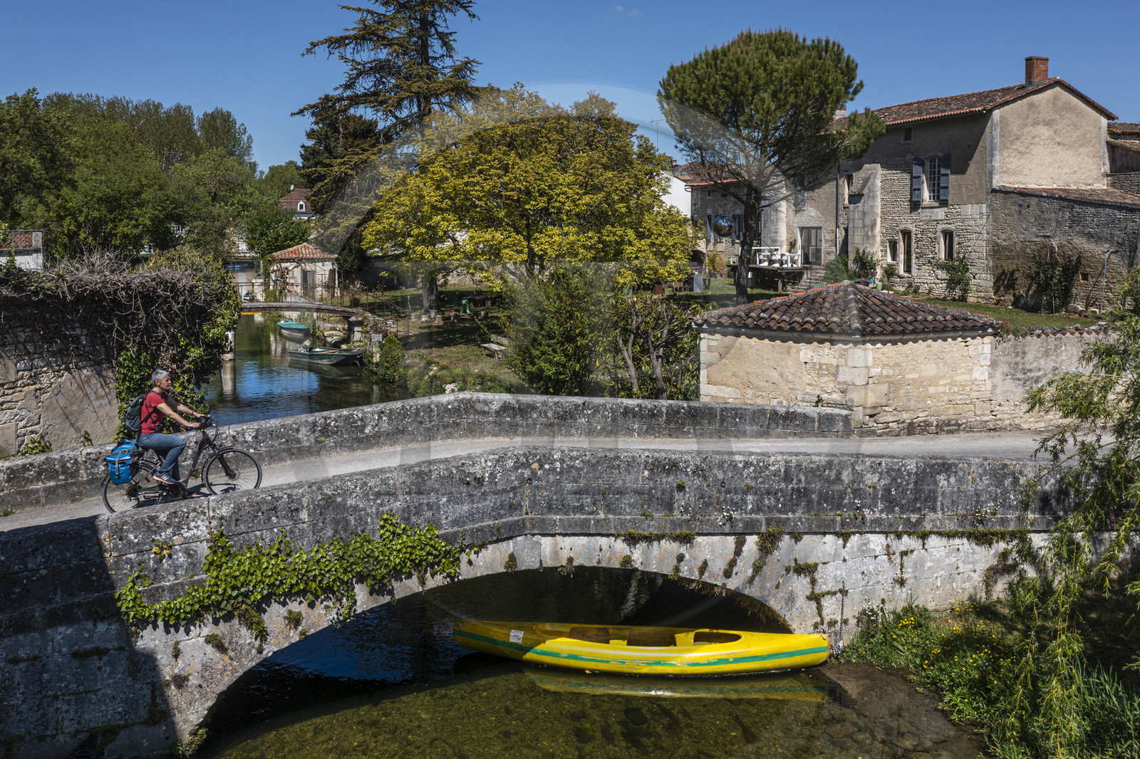 France, Charente (16), Bassac, cycliste faisant la véloroute La Flow Vélo passant le pont sur la Guirlande, un petit affluent du fleuve La Charente qui traverse le pied du bourg (vue aérienne)