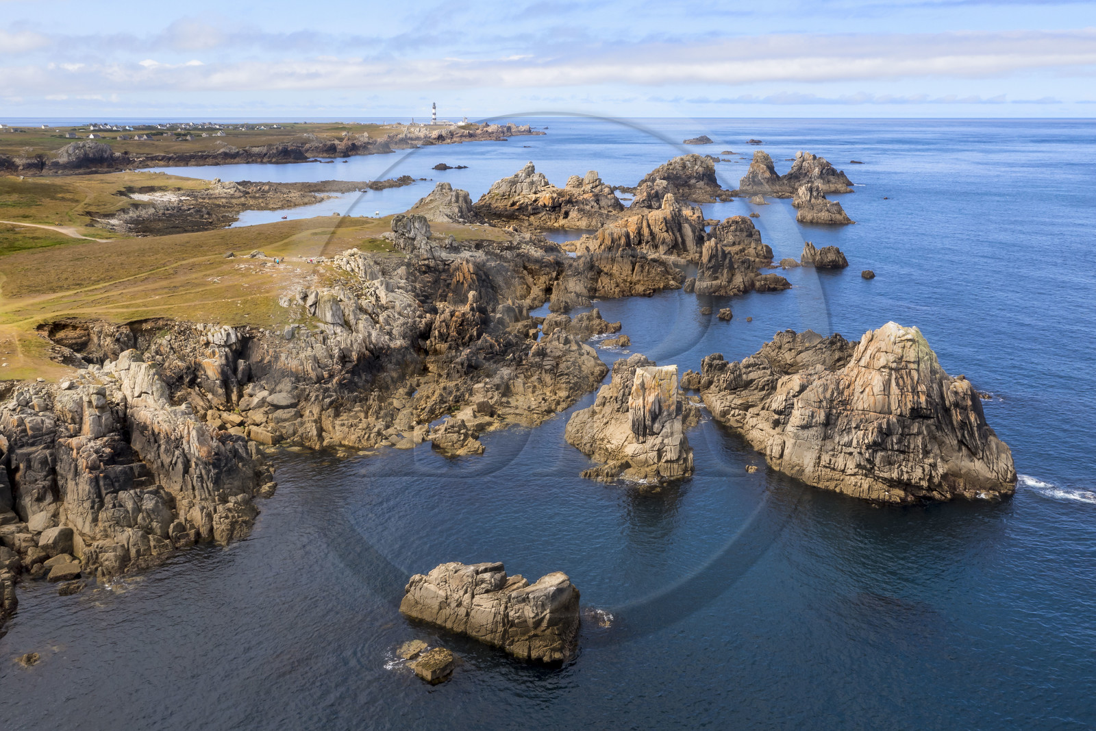 France, Finistère, Iroise Sea, Ouessant Island, the jagged coast and the rocks of the north coast, the Creac'h lighthouse in the background (aerial view)
