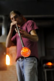 France, Moselle (57), Meisenthal, Thibaut souffleur au Centre international d’Art verrier (CIAV), fabrication d'une boule de Noël en verre. Tout en tournant la canne, il souffle dans la canne