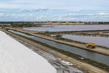 France, Gard (30), Aigues-Mortes, la ville médiévale entourée par ses remparts en bordure des marais salants (Salins du Midi) depuis une montagne de sel stocké